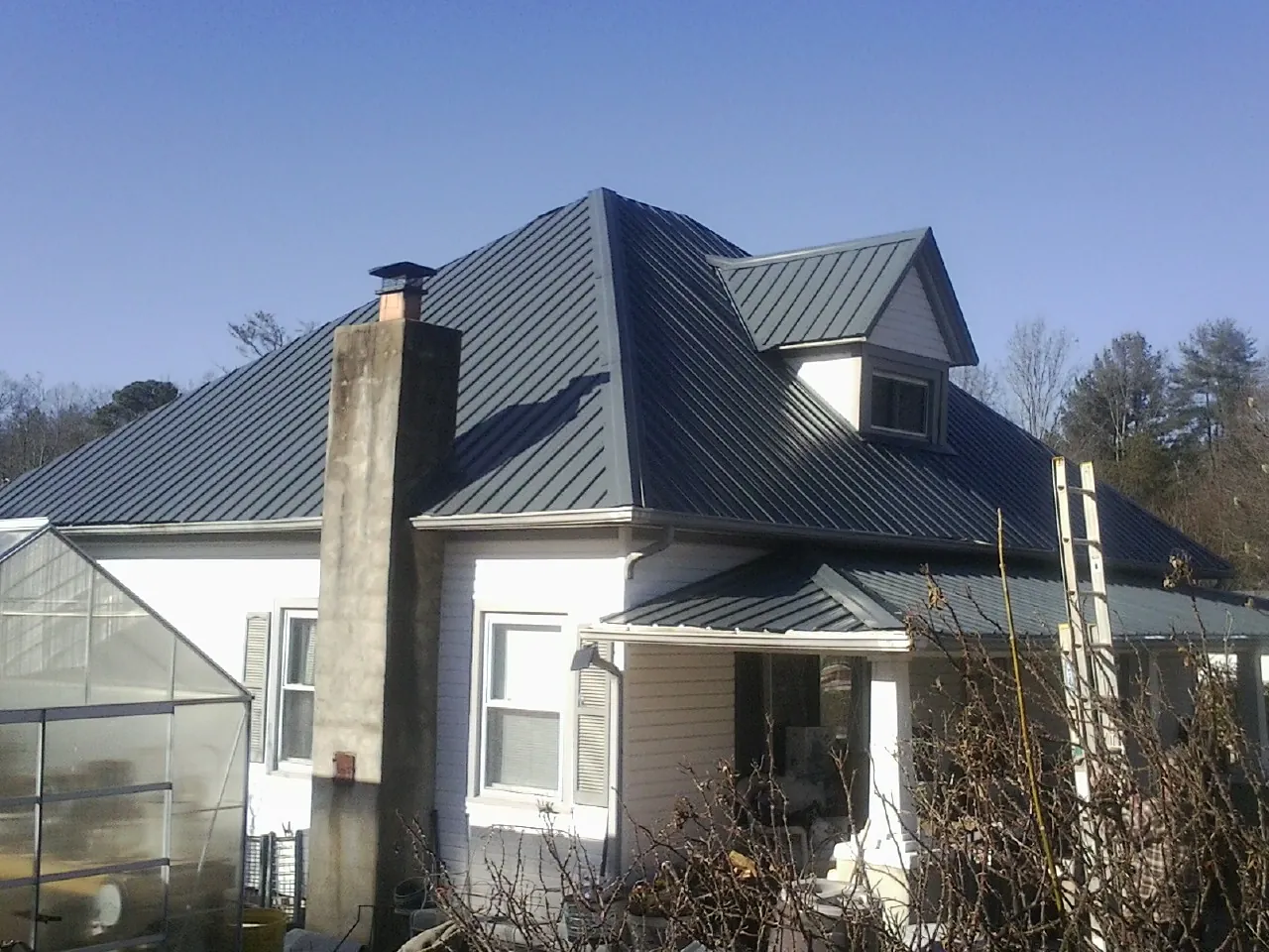 Dark blue standing seam metal roof on a white farmhouse with dormer — Slate & Tile Roof Repair by Roofing Brothers in Roselle Park