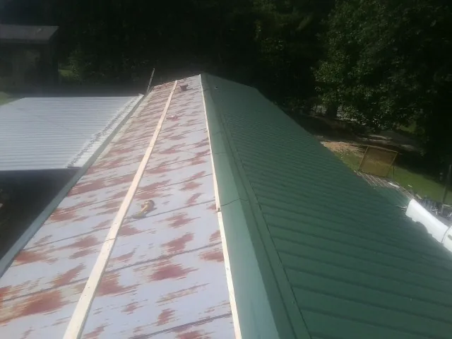 Old rusted panels beside newly installed green metal roofing — Wind Damage Roof Repair by Roofing Brothers in Roselle Park