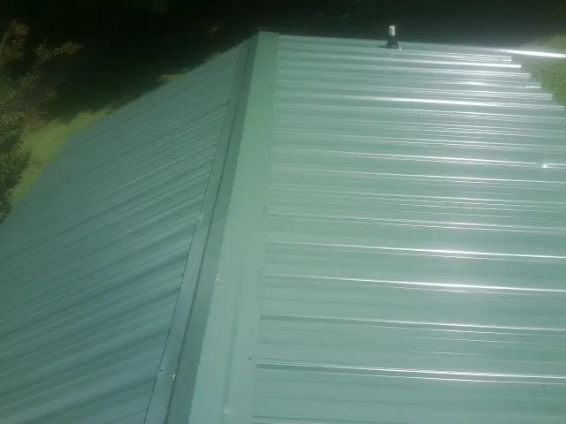 New green metal panels meeting at the ridge of a roof — Flat Roof Repair work by our crew in Roselle Park