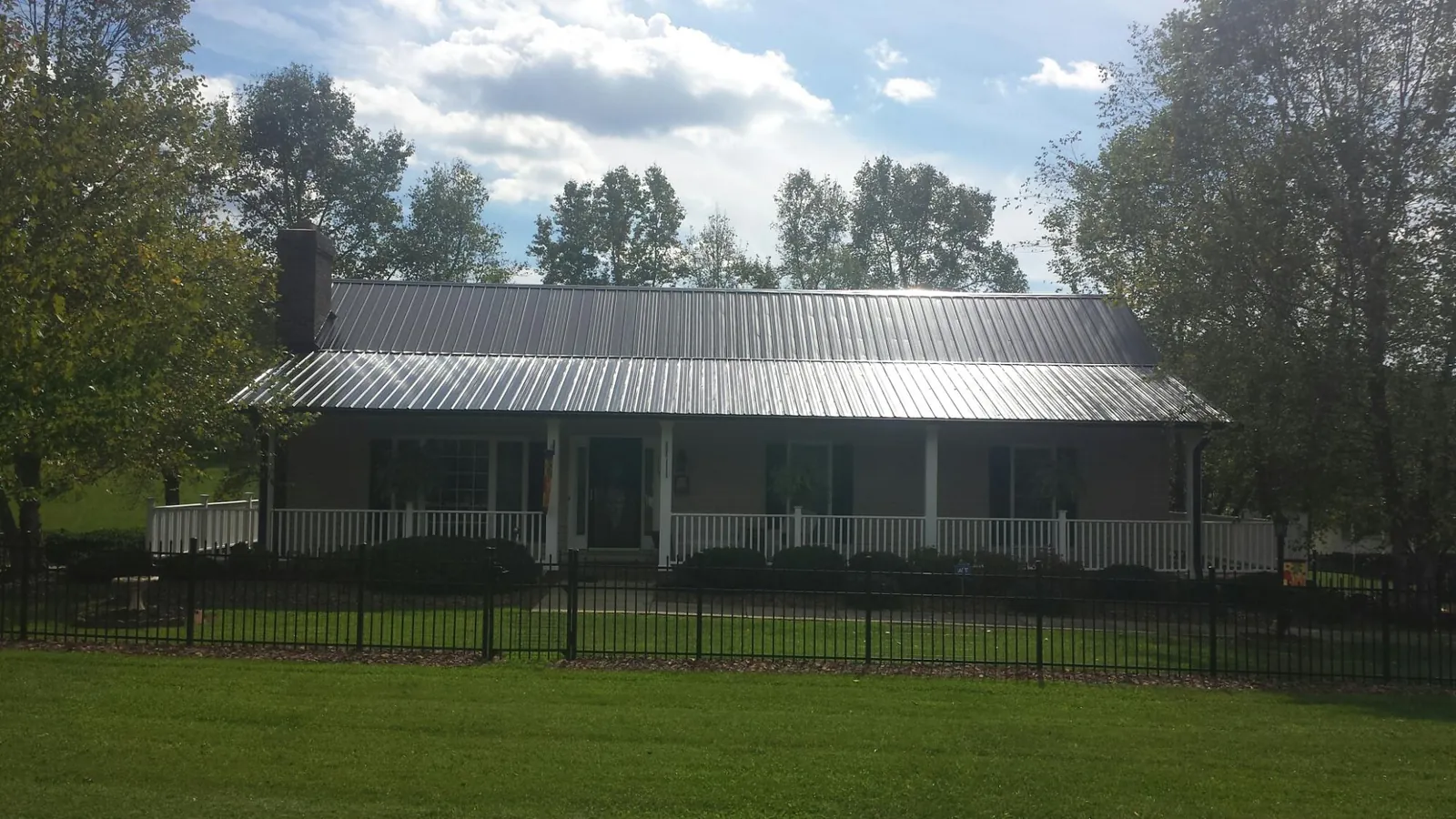 Gray metal roof on a brick ranch with a full width front porch — Gutter Guard Installation work by our crew in Roselle Park