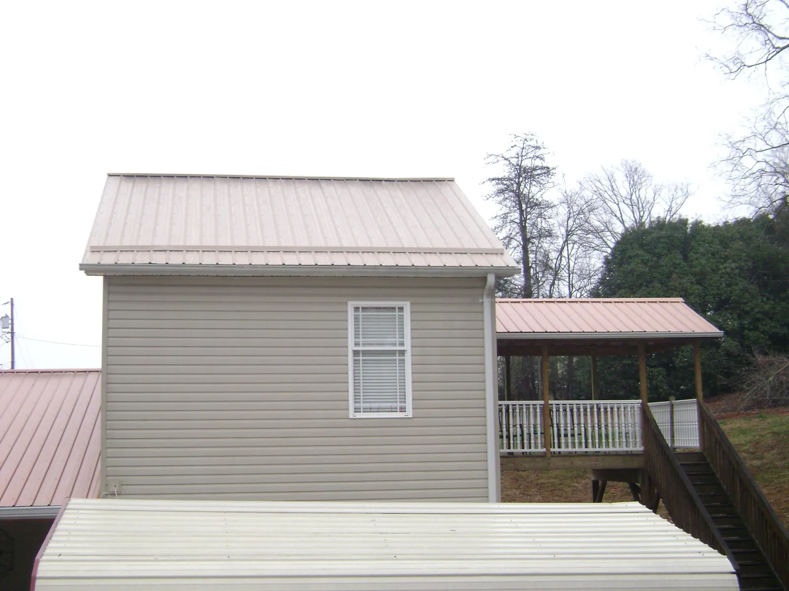 Tan metal roofs on a two story addition and attached porch, from a Roof Replacement job in Roselle Park