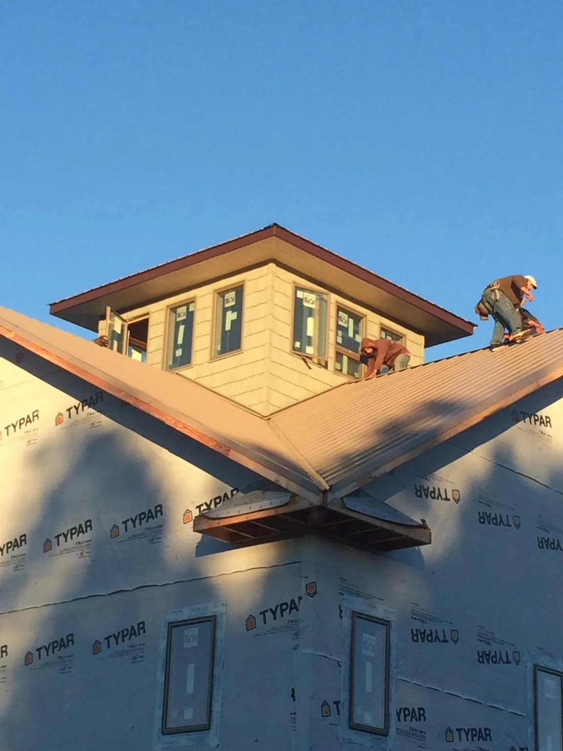 Roofers working around a rooftop cupola on a new metal roof at sunset — Roof Waterproofing in Roselle Park by Roofing Brothers